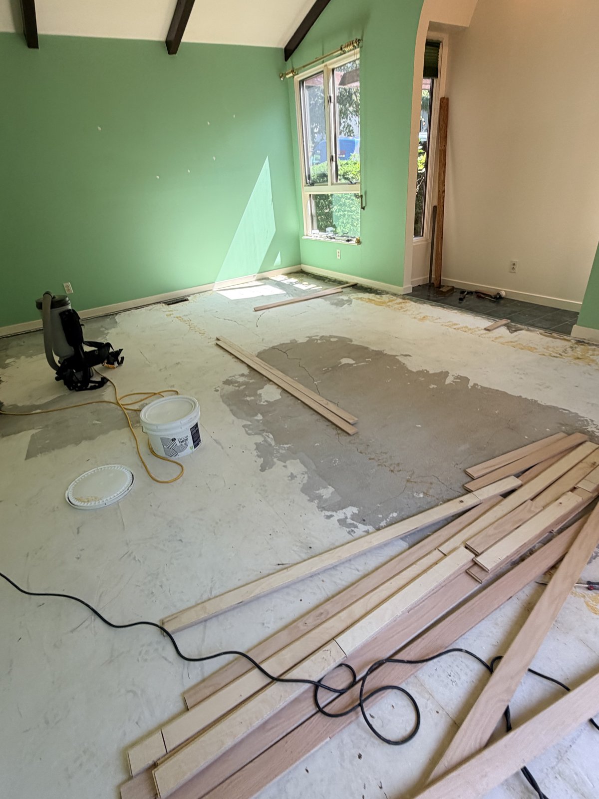 Green room with bare subfloor and new engineered hardwood planks laid out before installation in a Columbia, MD home