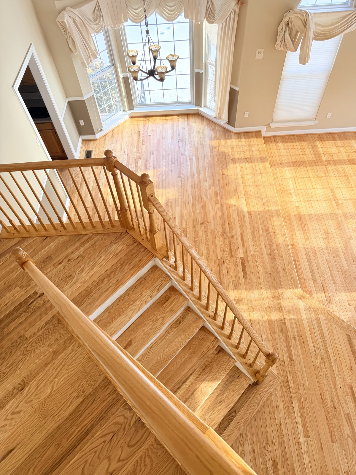 Refinished hardwood staircase and living room floors with warm amber polyurethane finish in Columbia, MD