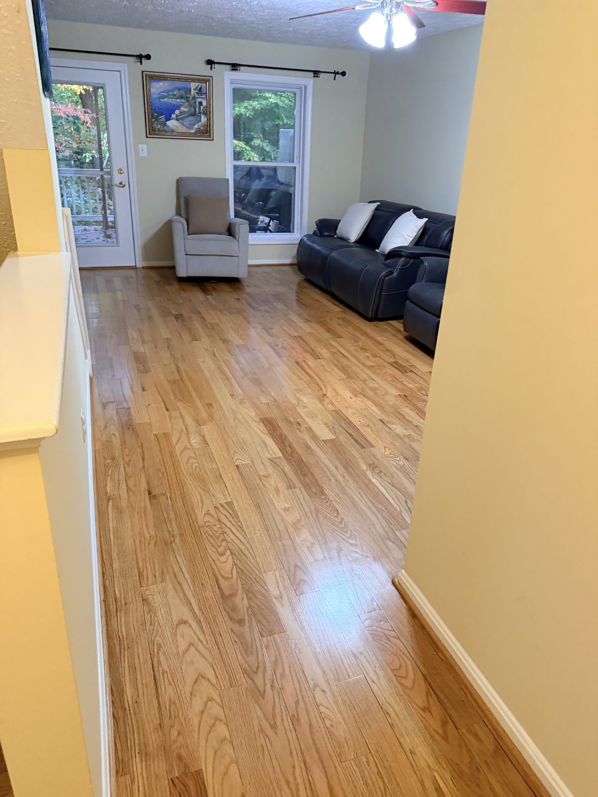 Refinished red oak hardwood floor with a gloss finish running from a hallway into a Germantown, MD living room