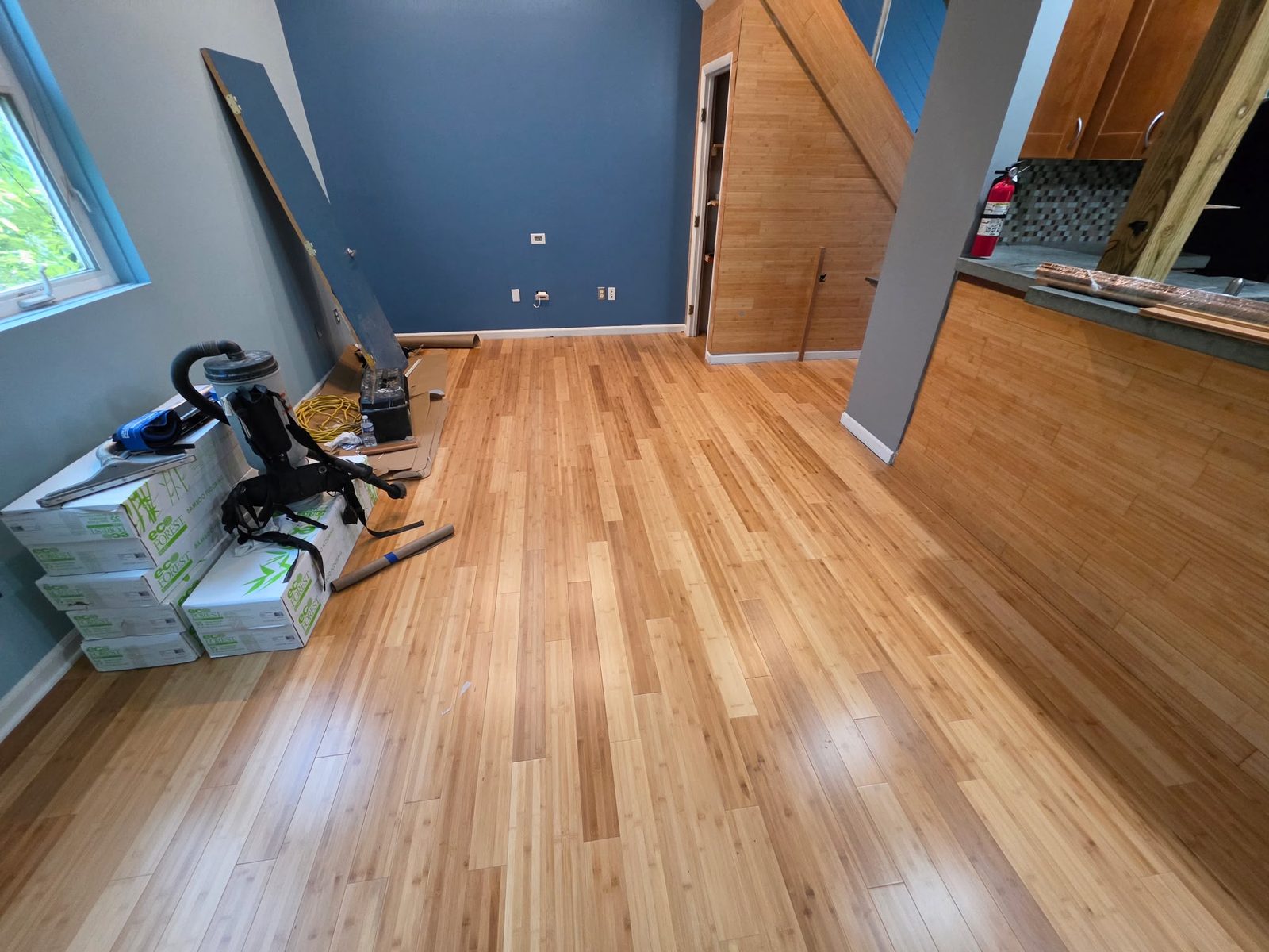 Hardwood flooring installation in progress with tools and flooring boxes