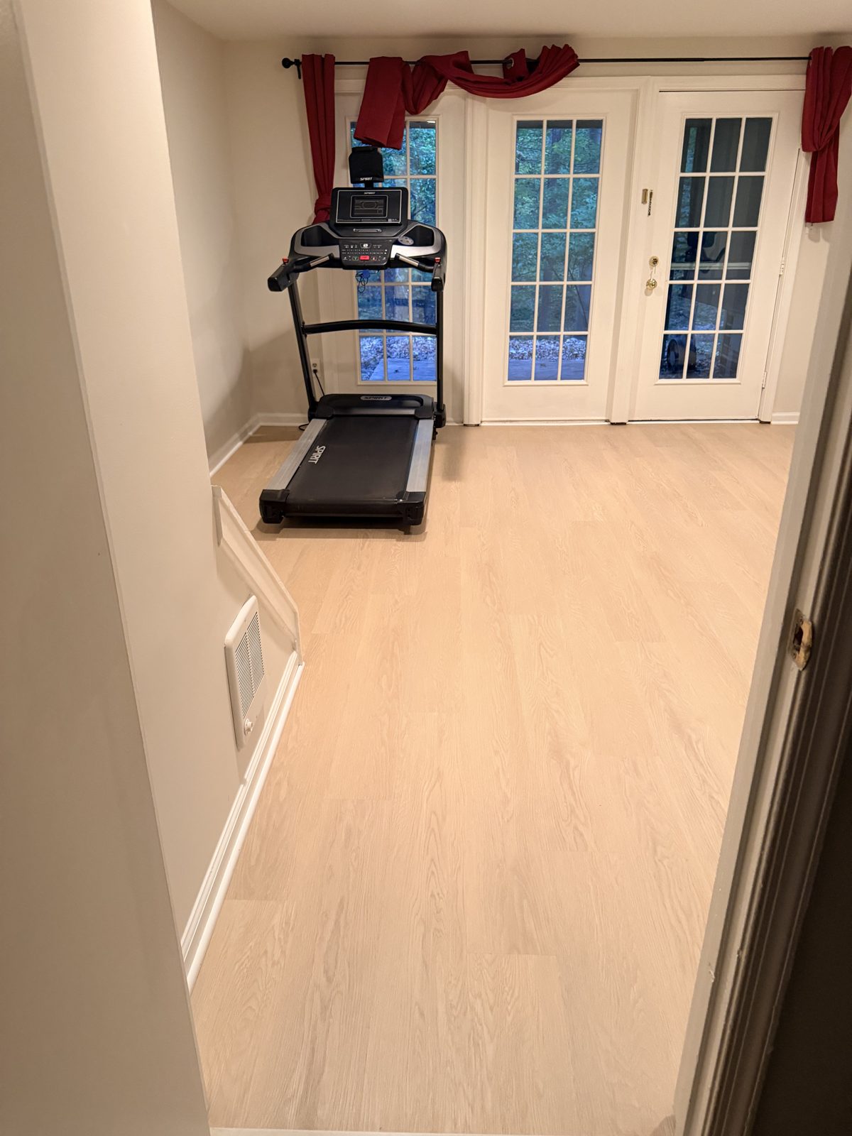 Luxury vinyl plank flooring running across a basement to French doors in Germantown, Maryland