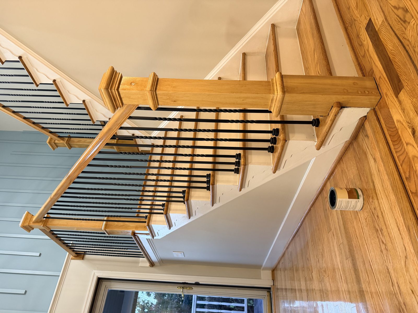 Refinished stairs with iron balusters and a wood handrail